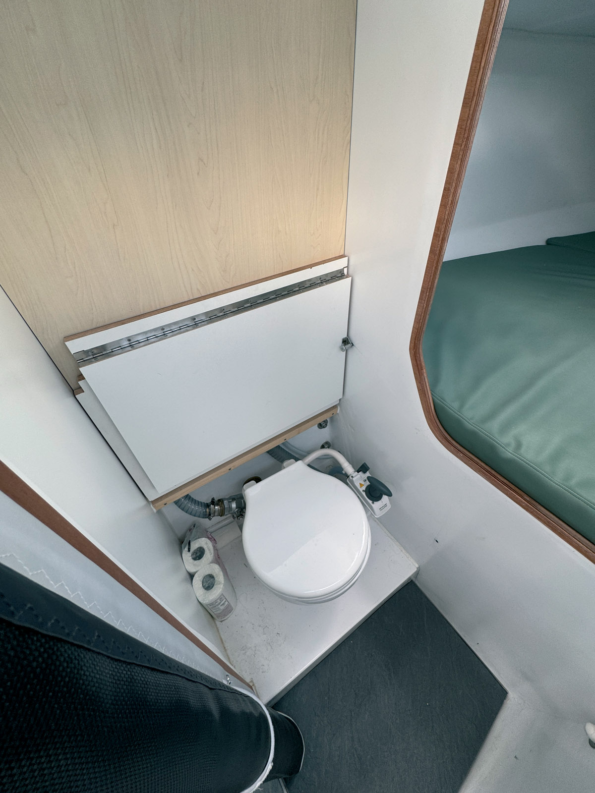 The heads compartment is located in the passageway with a clever toilet that disappears under a movable cabinet.