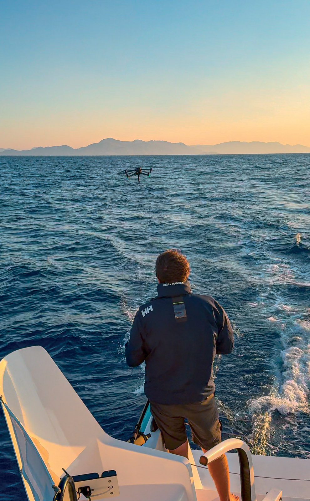 Carefully approach from  behind the multihull.